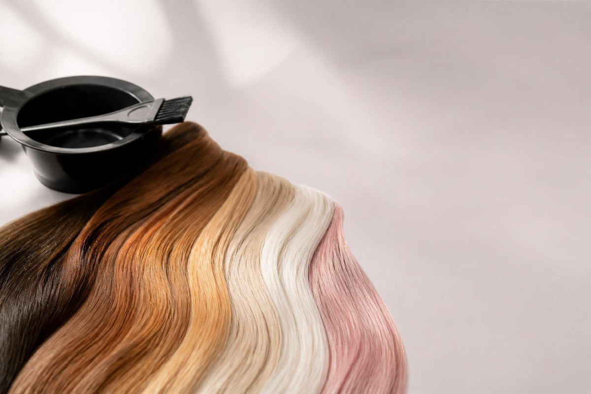 Mechones de cabello en tonos castaño, cobre, rubio, platino y rosa junto a un bowl de mezcla